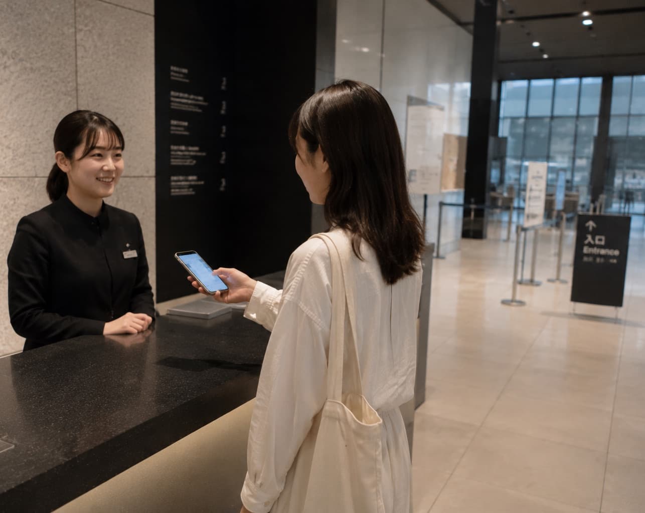 美術館の受付で、スマホに表示したチケットをスタッフに見せる来館者